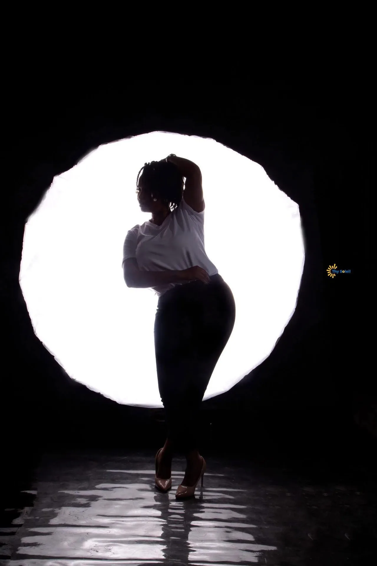 Silhouette photographiée devant une source lumineuse ronde.